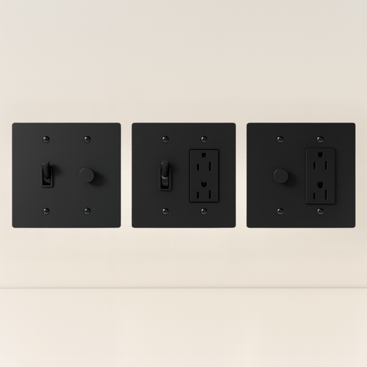 Three black wall switches and outlets on a beige background