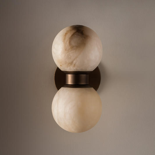 Wall-mounted light fixture with two spherical glass shades on a neutral background