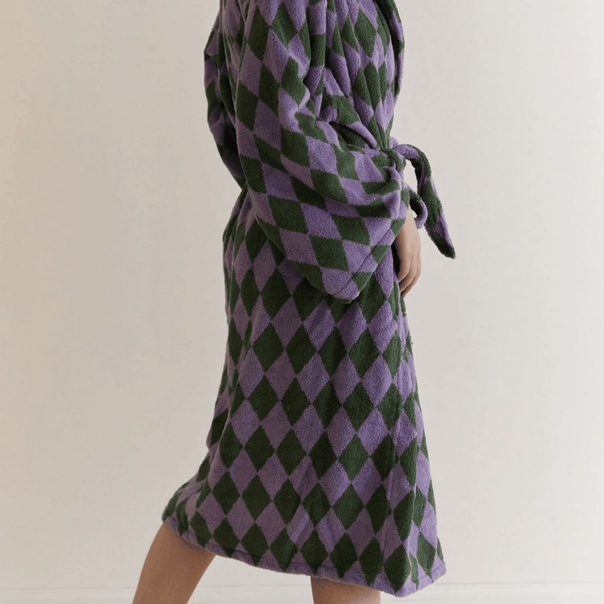 Person wearing a purple and green checkered dress against a plain background