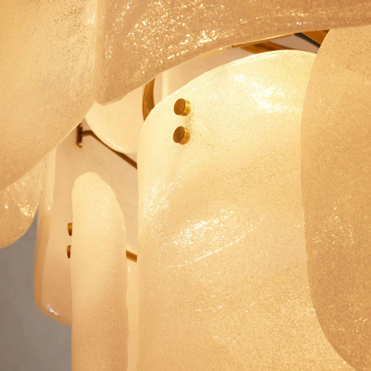 Close-up of a chandelier with textured glass shades and gold accents.