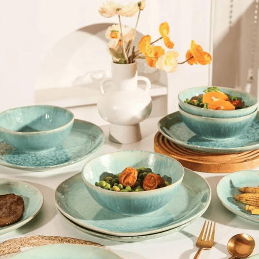 Set of blue ceramic dishes with food on a table with a vase of flowers in the background.