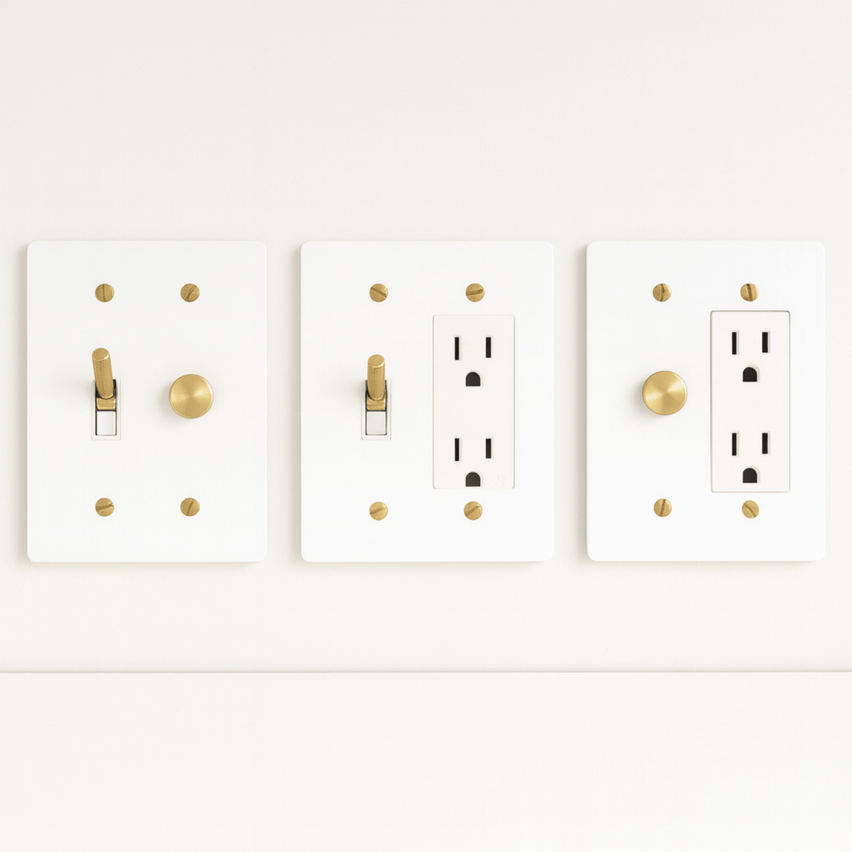 Three white light switch and outlet covers with gold accents on a white background