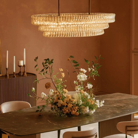 Dining room with a chandelier, marble table, and floral arrangement.