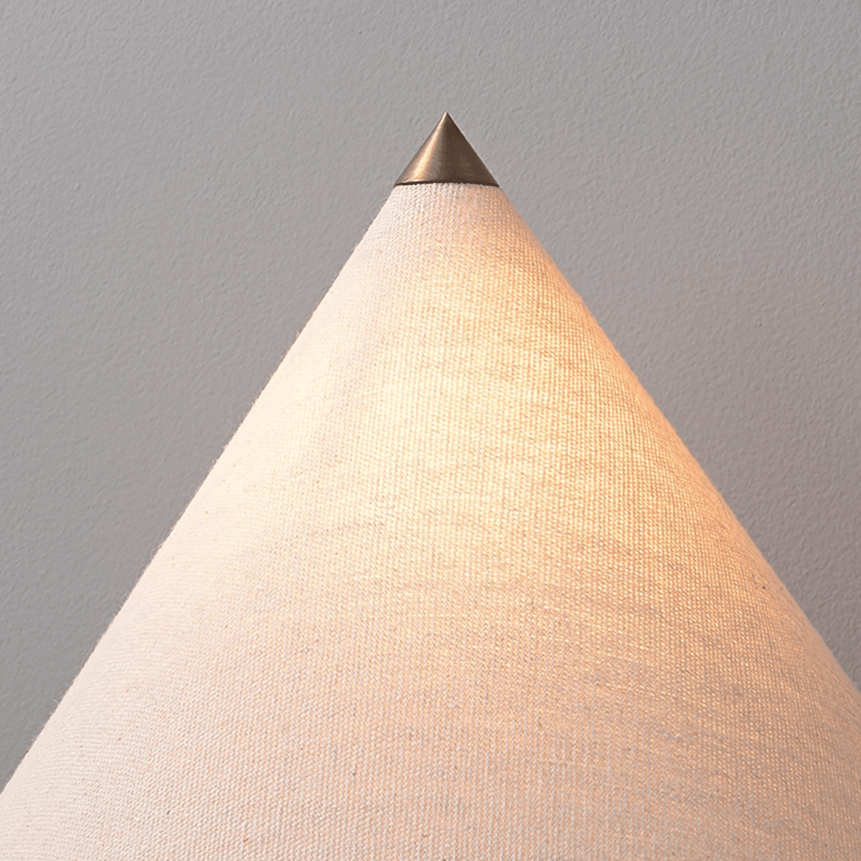 Conical lamp with a metallic top on a plain background