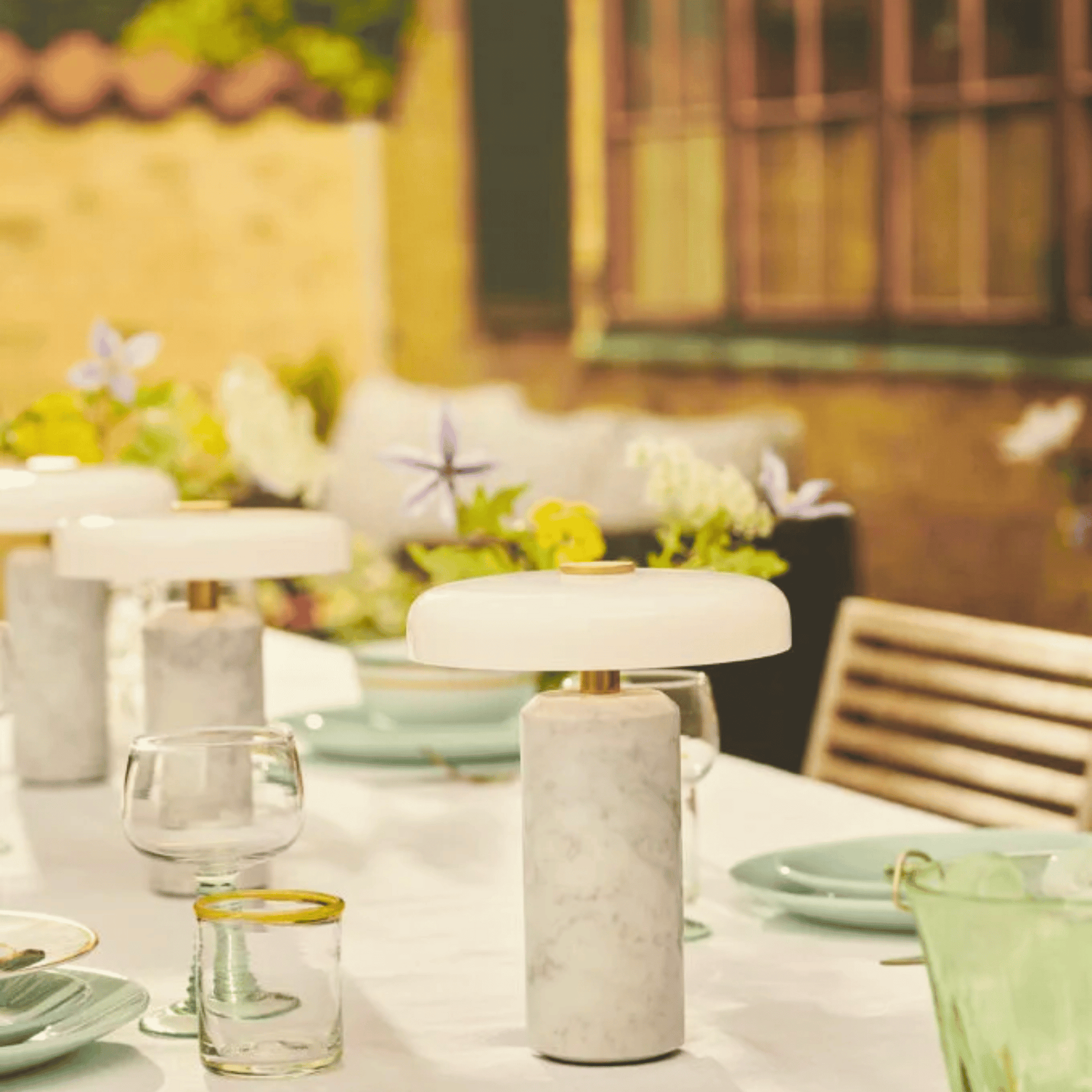 Outdoor table setting with a lamp and glasses on a blurred background