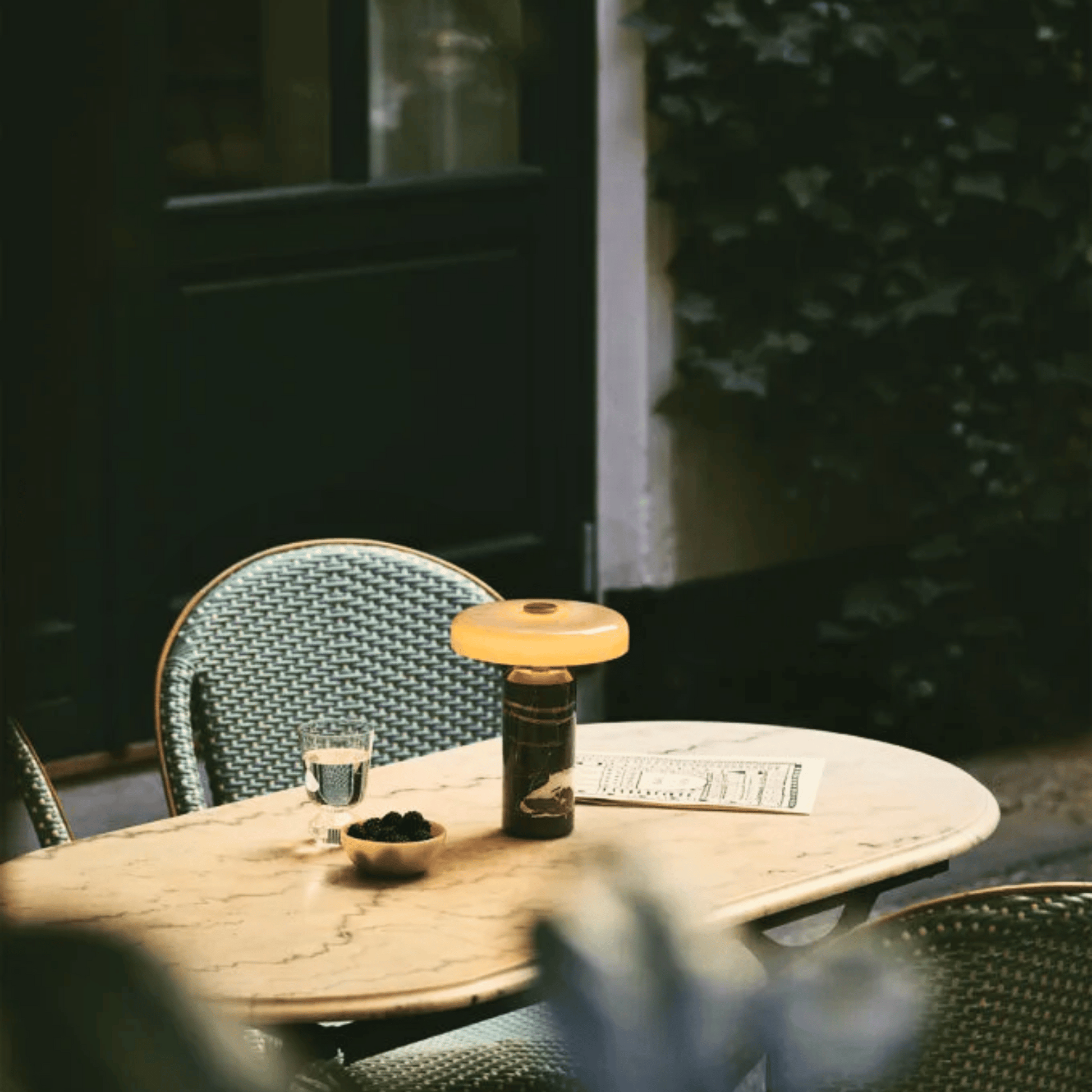 Outdoor table setting with a drink, snacks, and a menu on a wooden table.