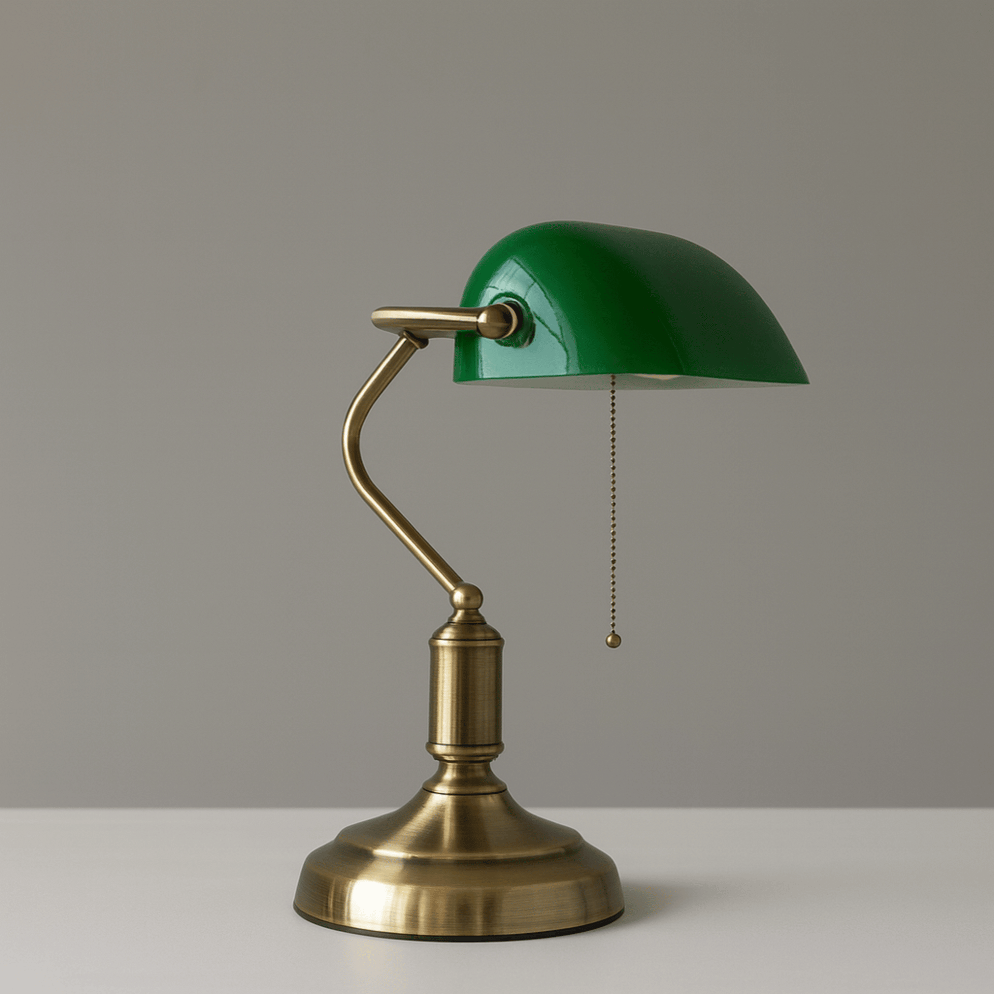 Vintage-style desk lamp with green shade and brass base on a neutral background