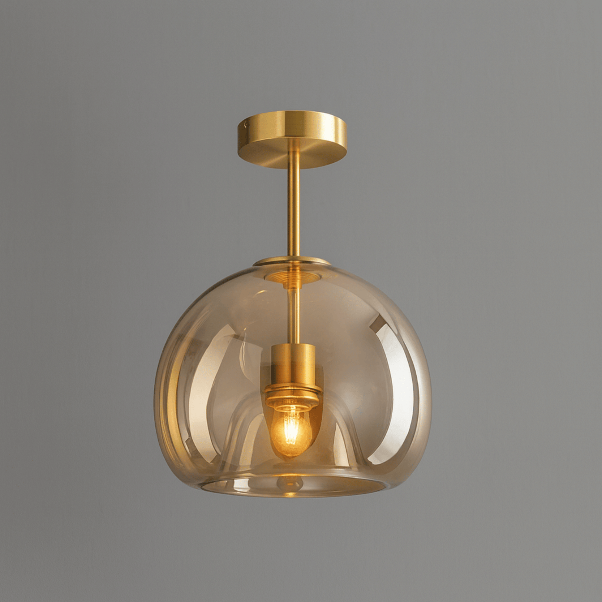 Gold pendant light with clear glass shade on a gray background