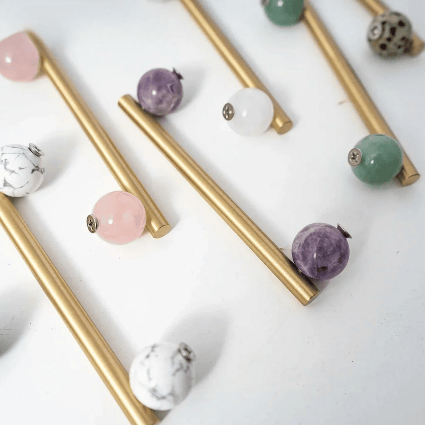 Gold cabinet knobs with various colored gemstones on a white background