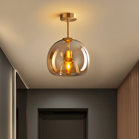Modern ceiling light fixture with glass shade and gold accents in a room setting.