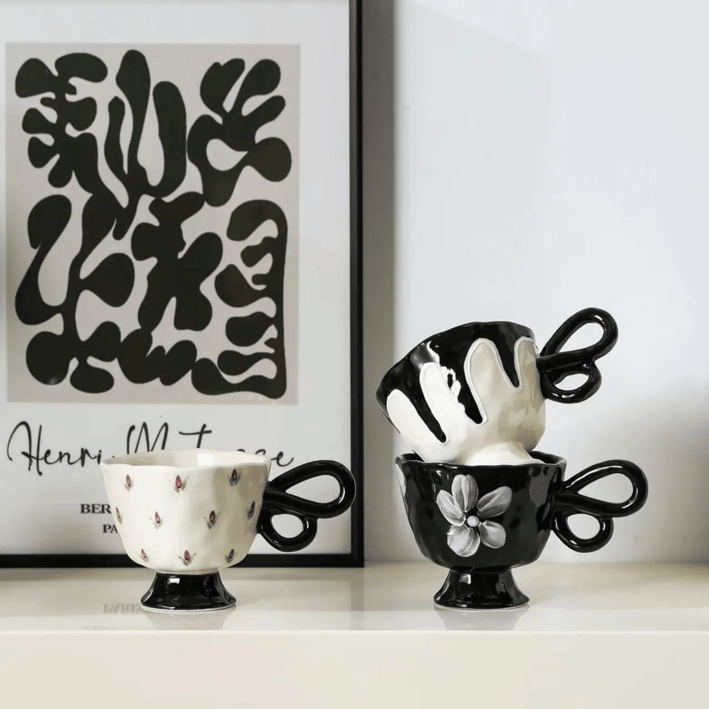 Black and white ceramic cups with abstract art in the background