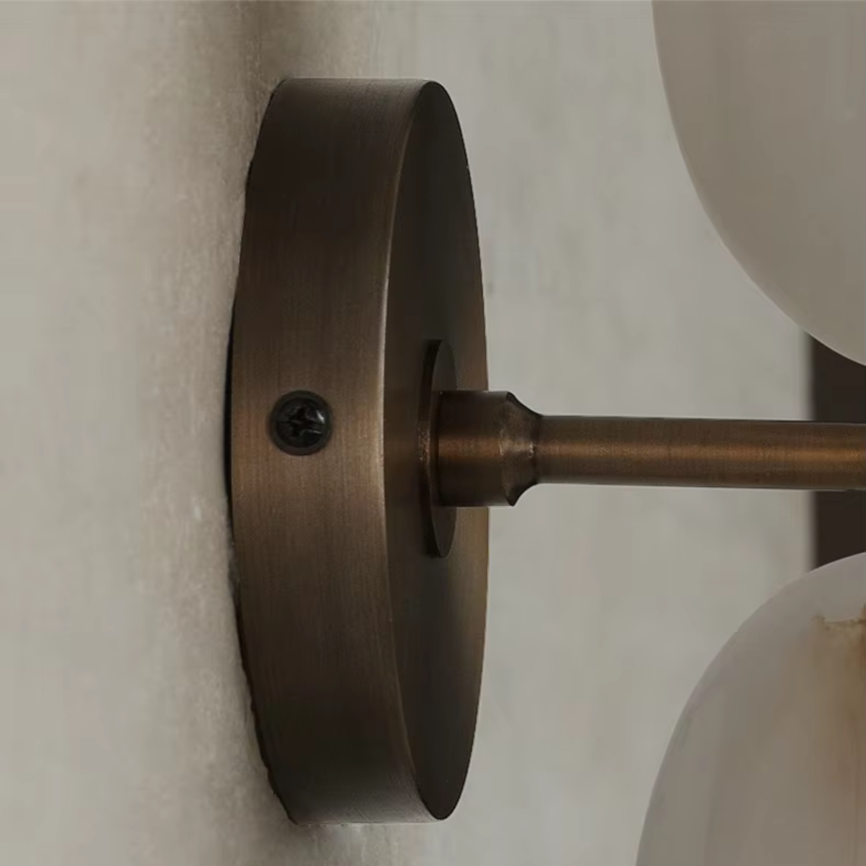 Close-up of a bronze wall-mounted light fixture on a neutral background
