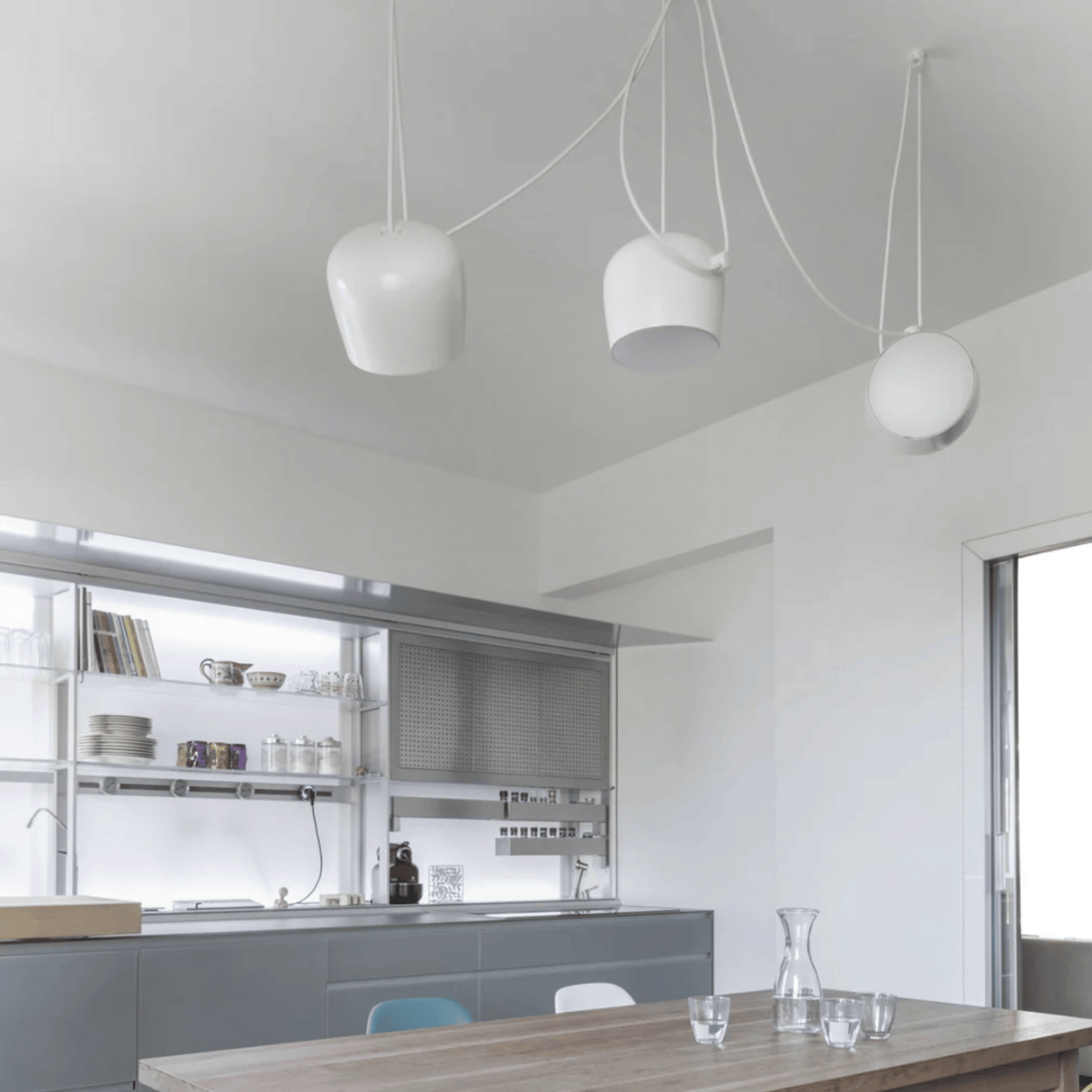 Modern kitchen with pendant lights and a dining table.