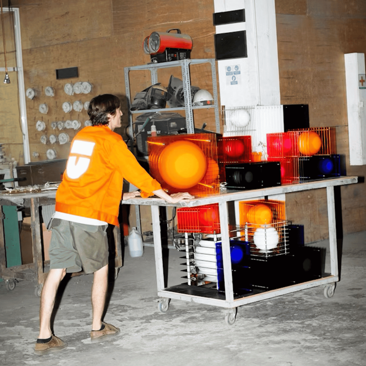 Person in orange hoodie interacting with a table full of colorful balls in a workshop setting
