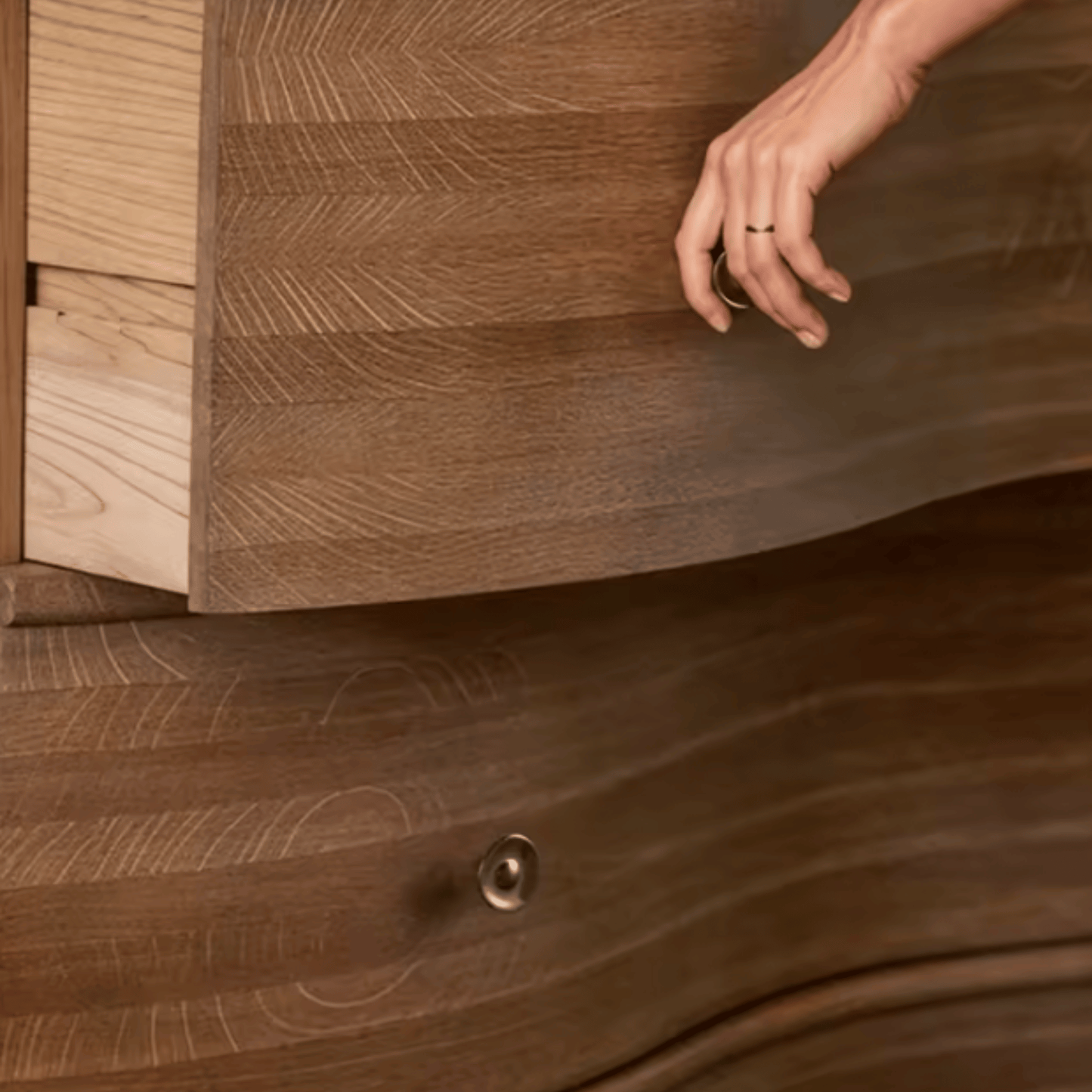 Wooden drawer being pulled open with a hand, showing wood grain and texture.
