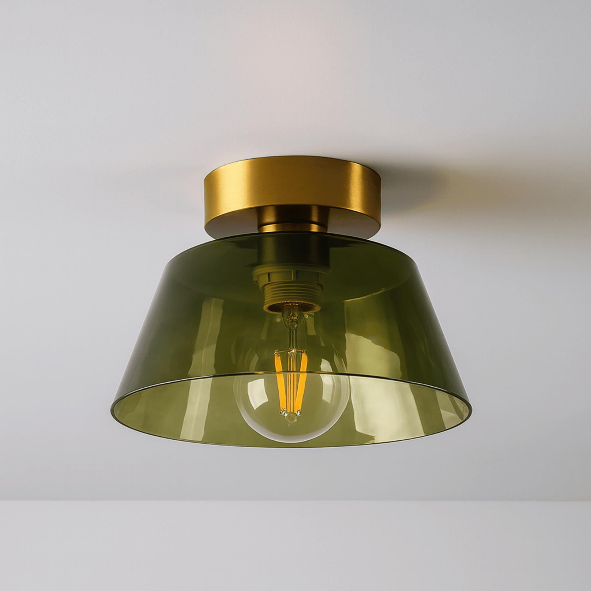 Ceiling light fixture with green glass shade and gold metal fixture on a white background