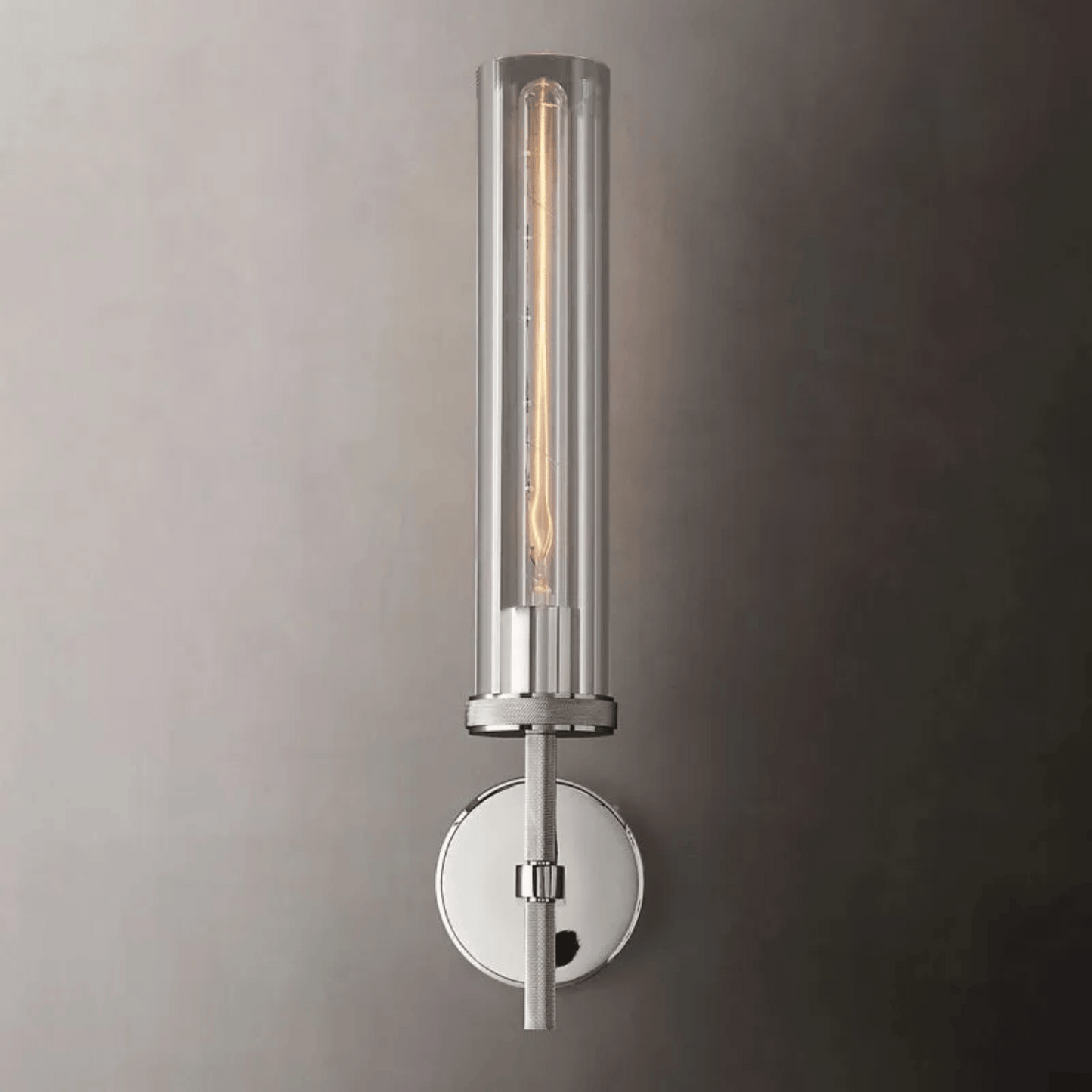 Wall-mounted cylindrical light fixture with clear glass cover on a gray wall.