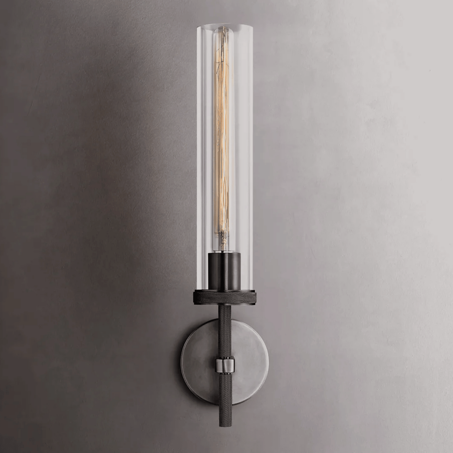 Modern wall sconce with clear glass shade on a gray wall