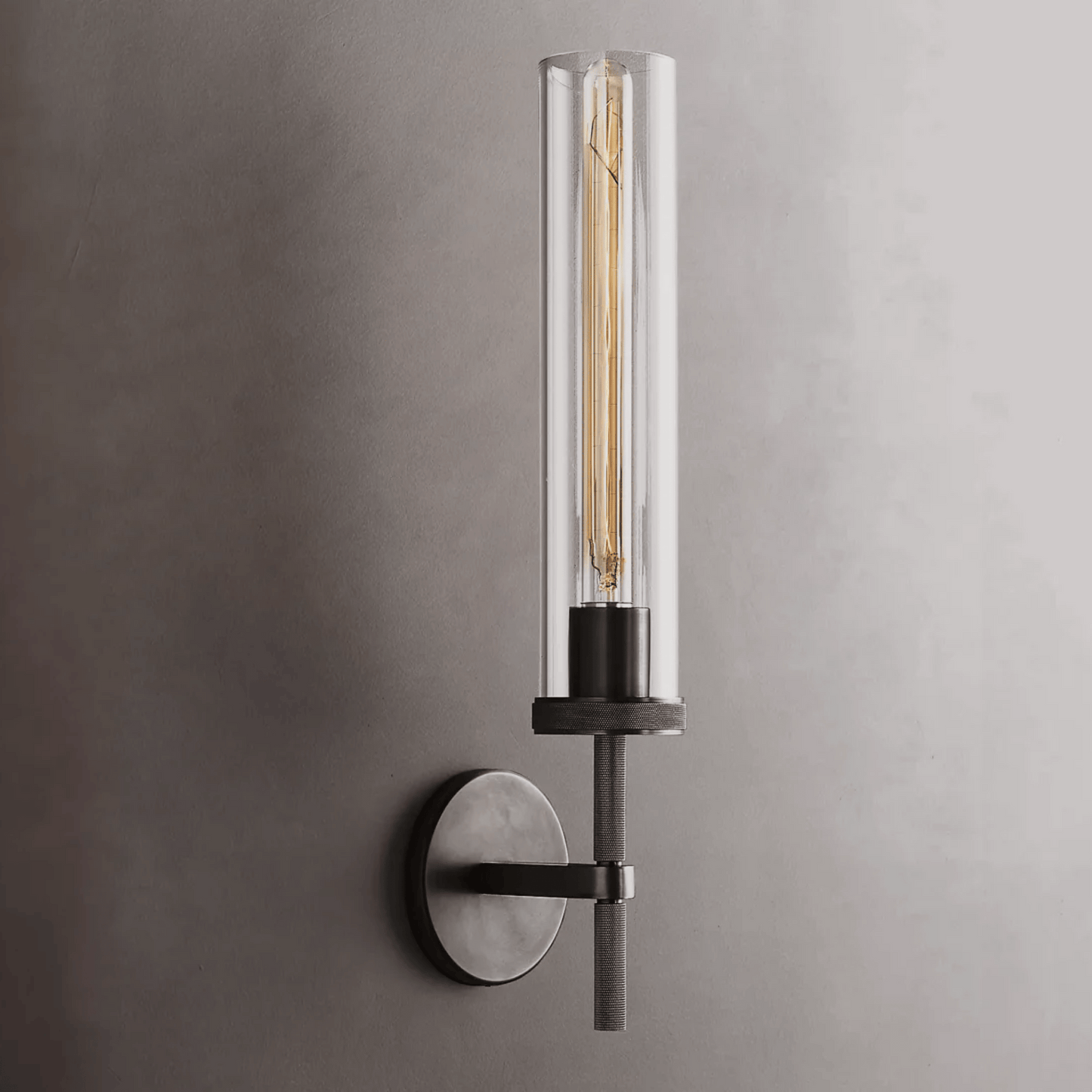 Modern wall-mounted light fixture with clear cylindrical glass shade on a gray background