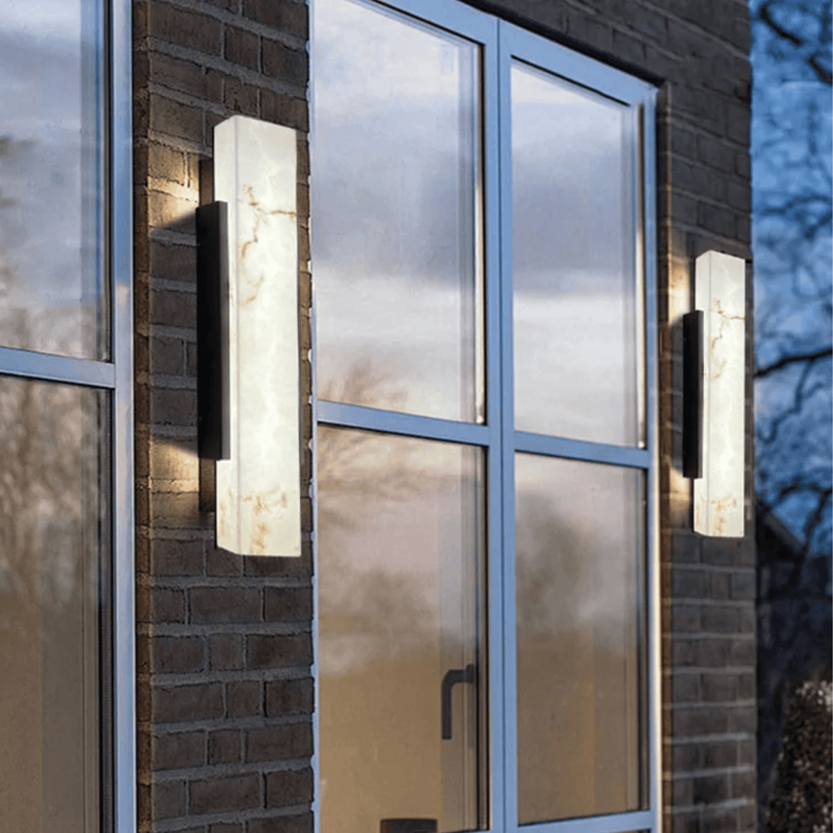 Modern outdoor wall lights on a brick building with glass windows.