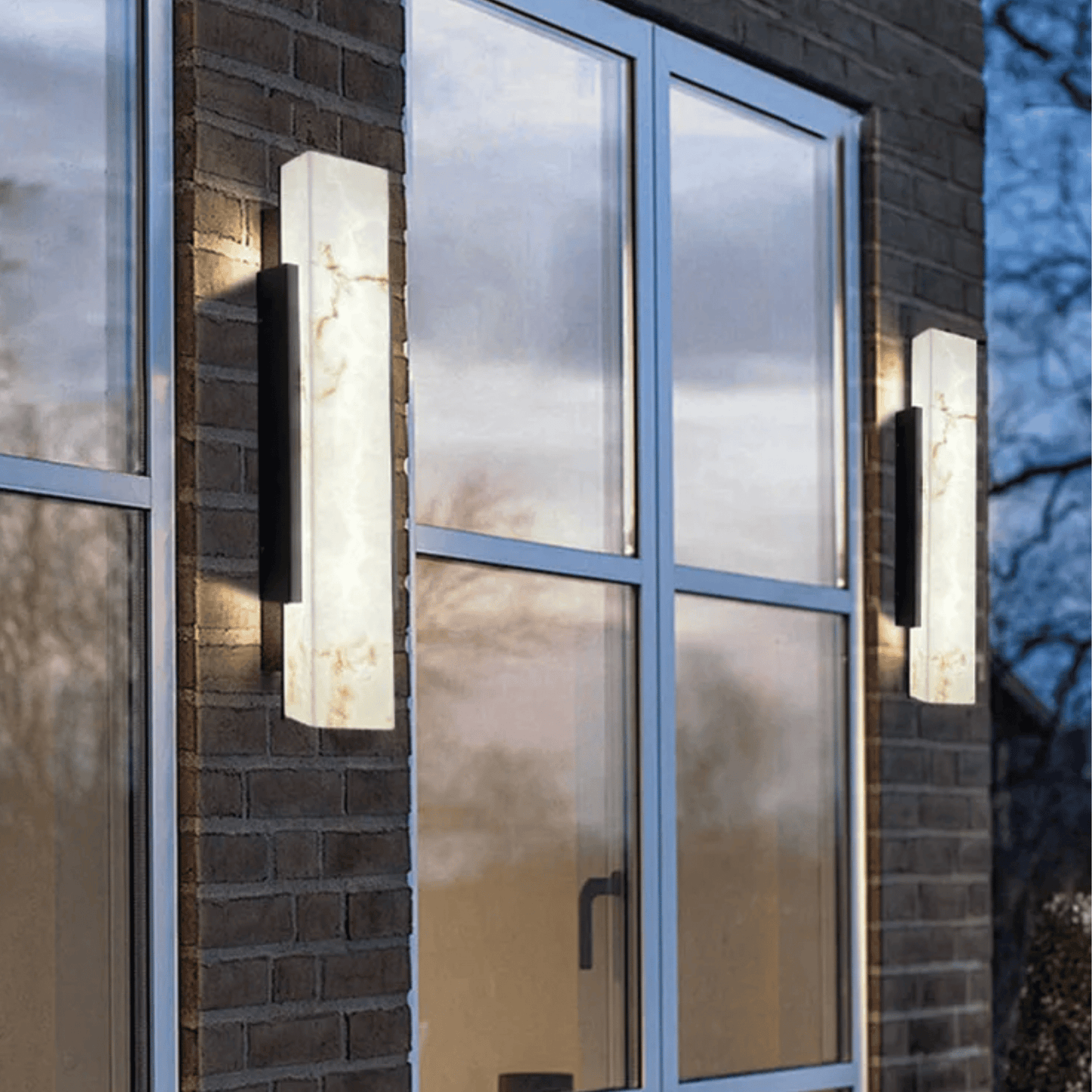 Modern outdoor wall lights on a brick building with glass windows.