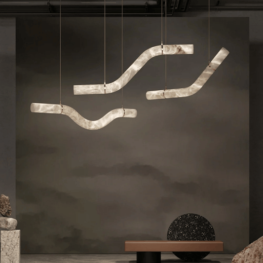 Modern pendant light fixture hanging against a dark wall with minimal decor.