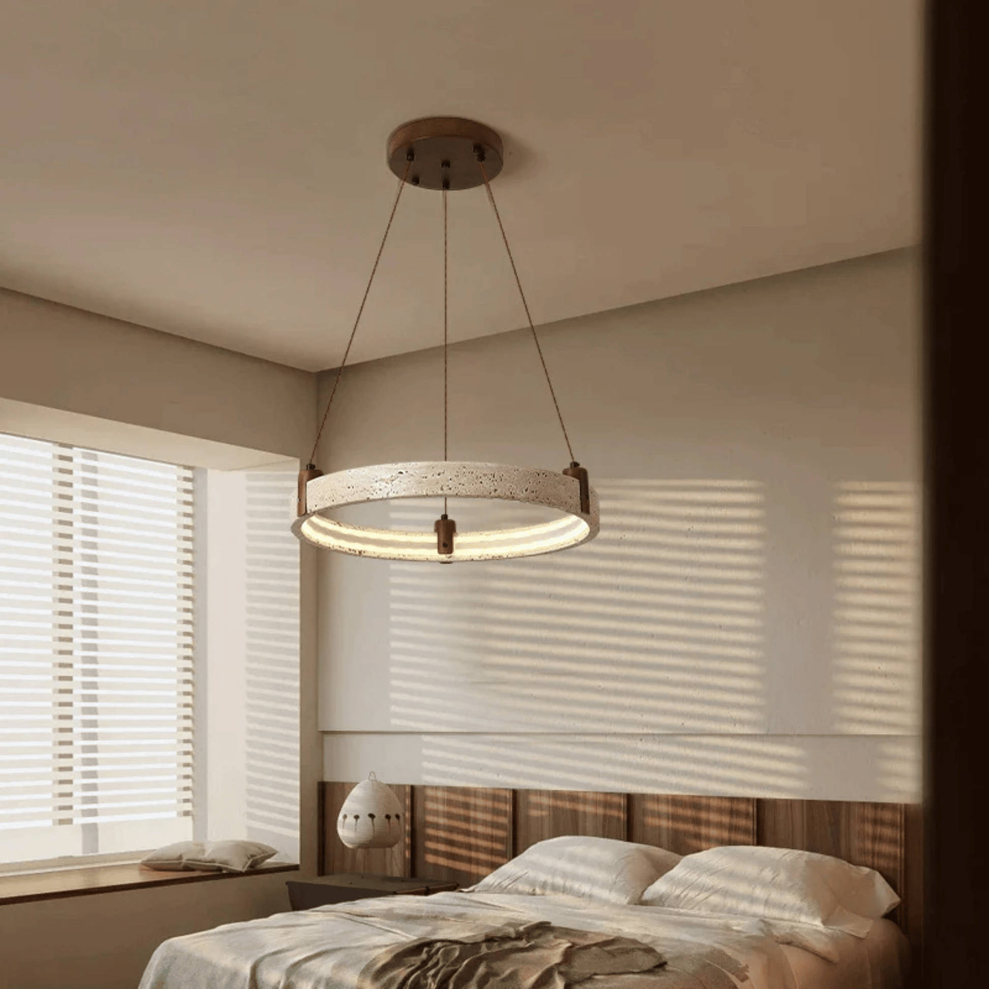 Modern pendant light hanging above a bed in a bedroom with neutral tones.