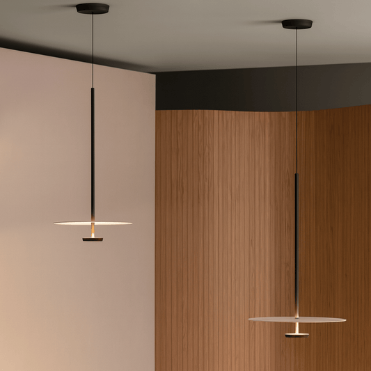 Two pendant lights hanging in a room with a wooden wall and neutral-colored ceiling.