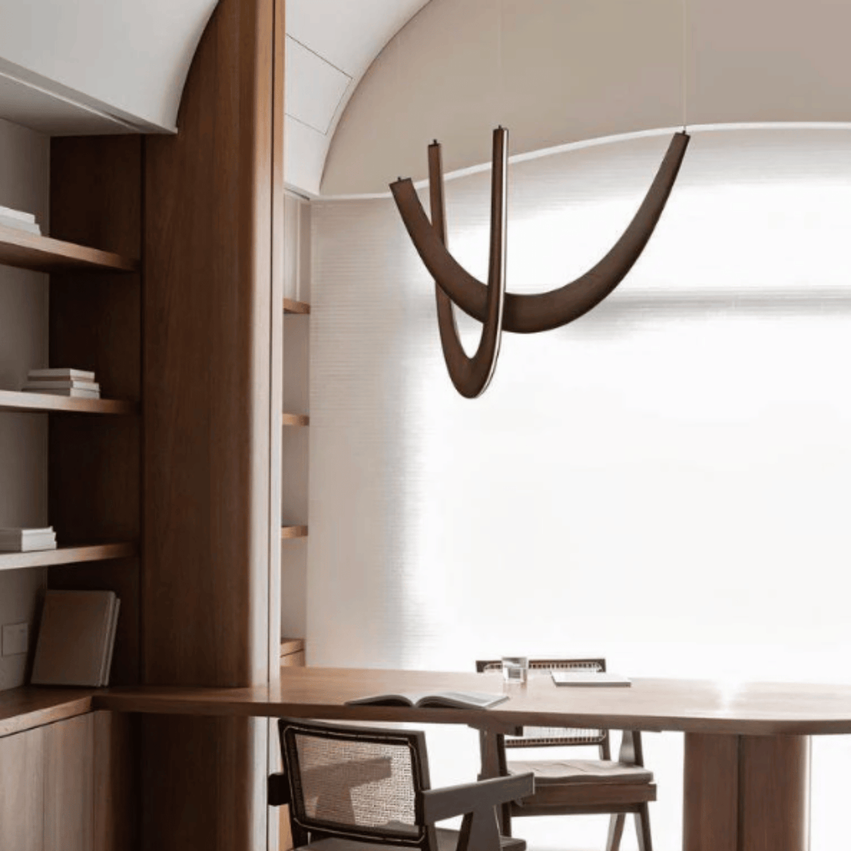 Modern office interior with wooden desk, chairs, and wall-mounted lamp.