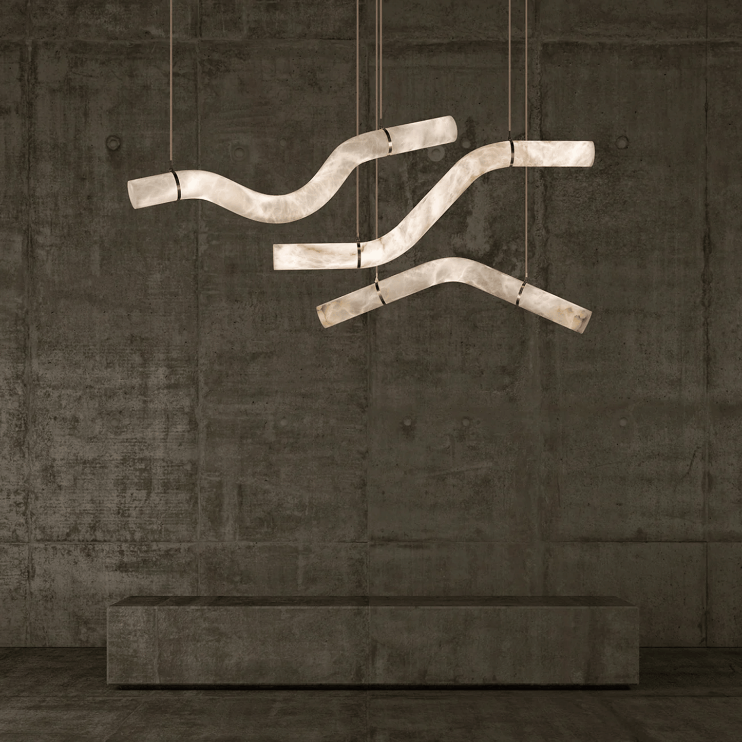 Modern chandelier with curved design hanging against a textured wall.