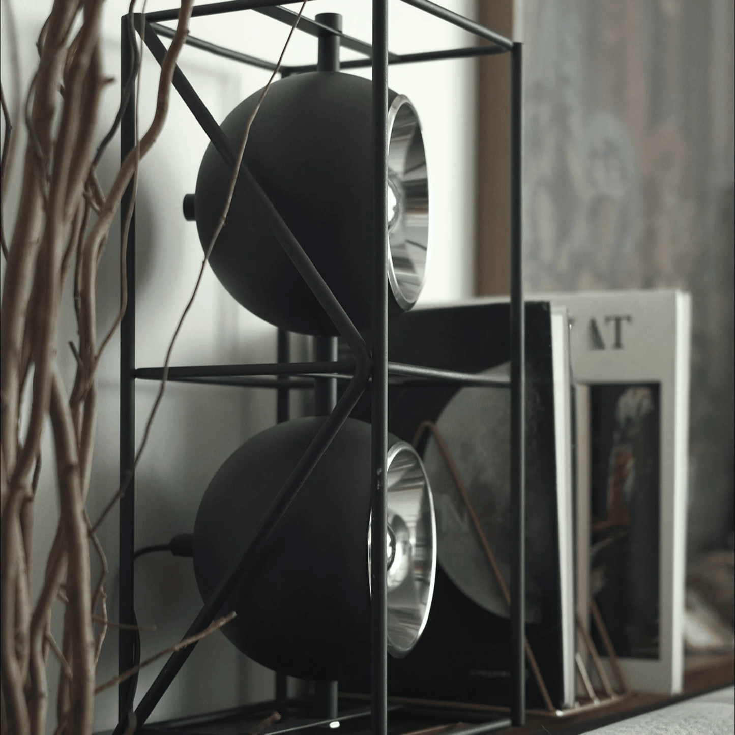 Decorative shelf with black spherical objects and books in a blurred indoor setting