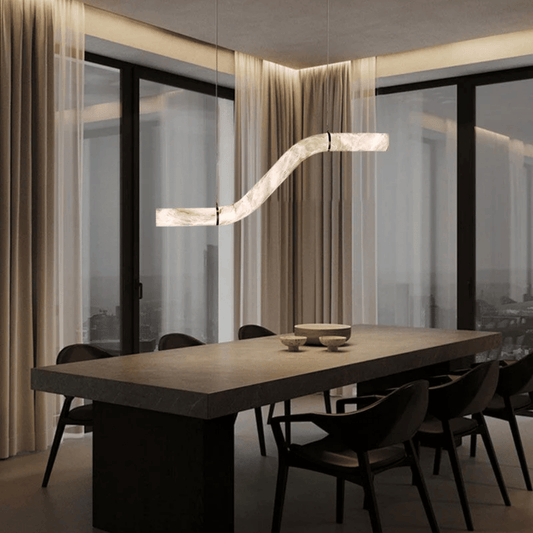 Modern dining room with a long table and chairs, featuring a stylish pendant light.
