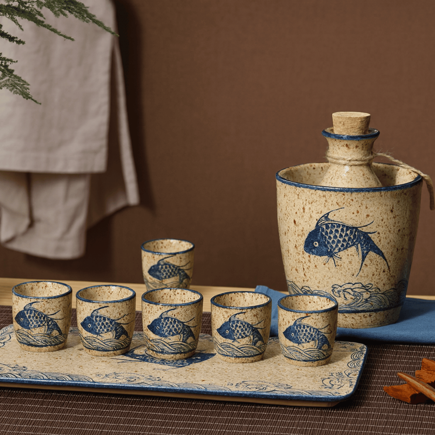 Ceramic sake set with fish design on a tray against a brown background