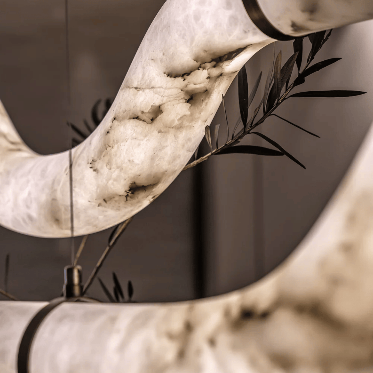 Close-up of a marble sculpture with olive branches against a neutral background