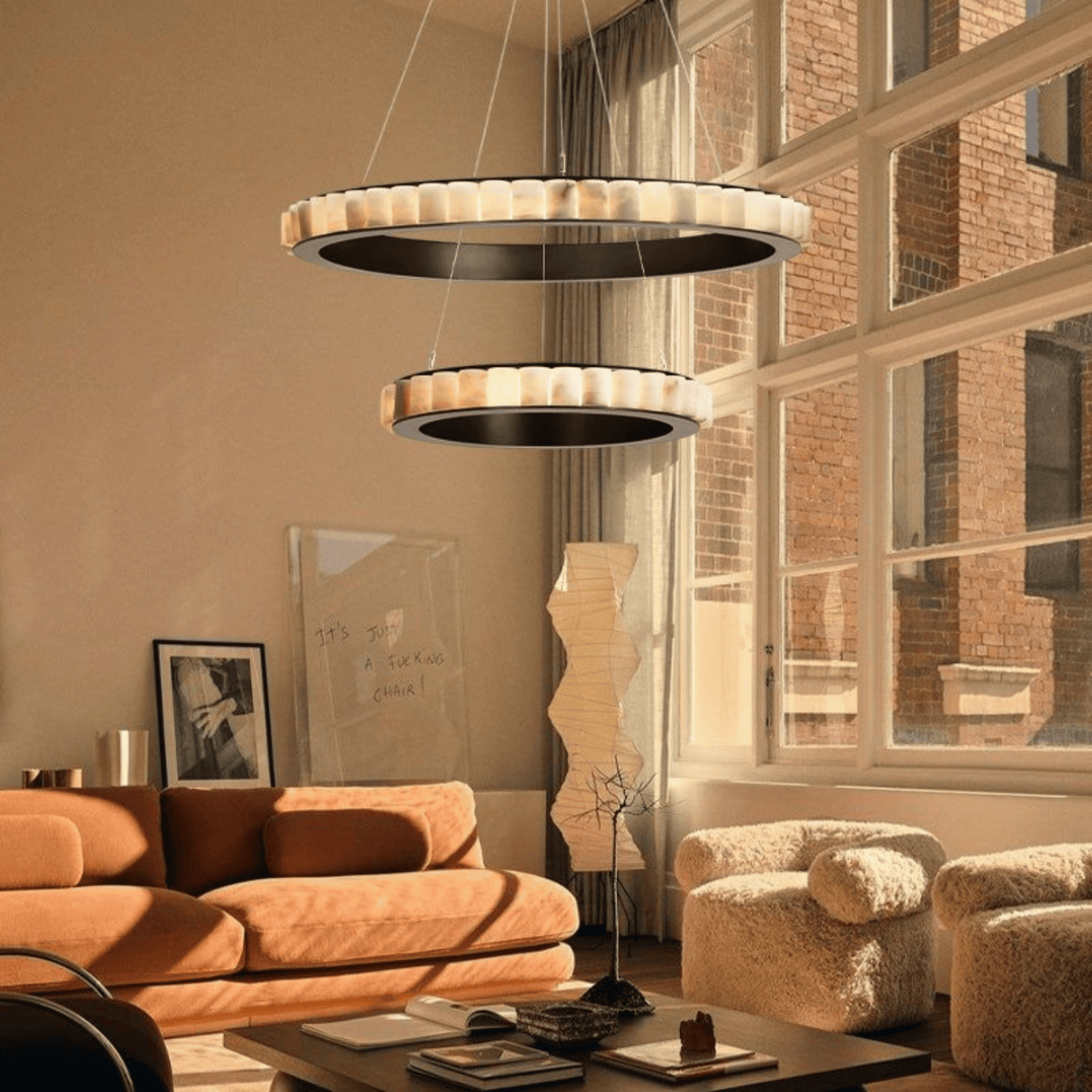 Modern living room with a stylish chandelier, orange sofa, and large windows.