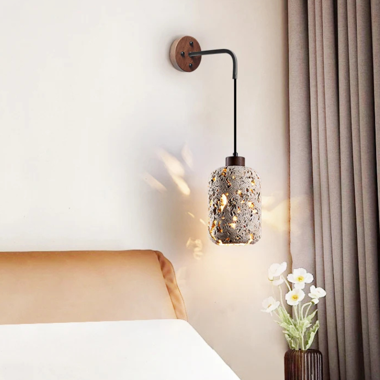 The same lamp glowing warmly above a beige bed, casting patterned light on the wall.