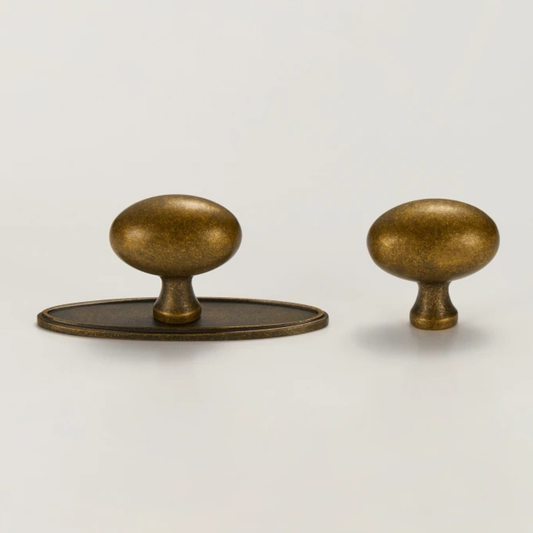 Two antique brass knobs placed side by side on a neutral surface.