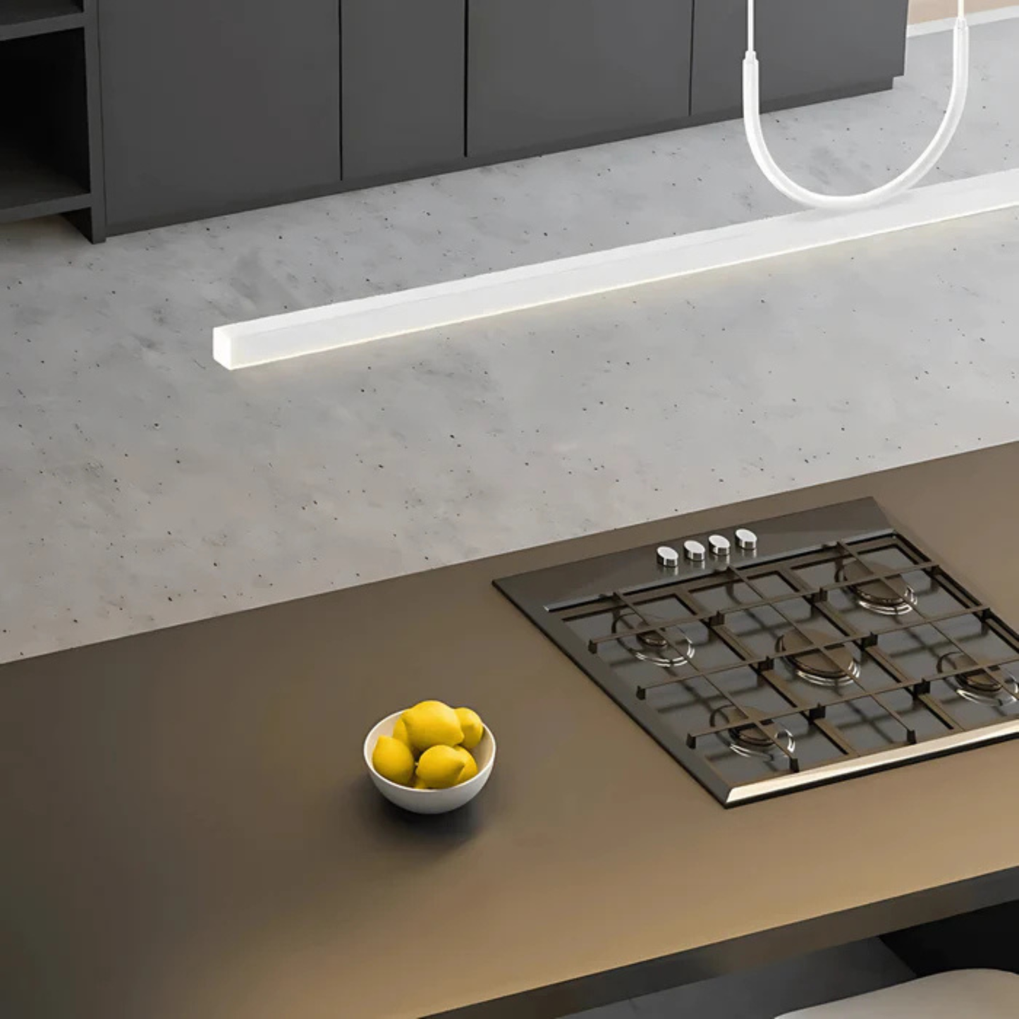 Contemporary kitchen countertop with a sleek white linear light fixture above a gas stove and a bowl of lemons
