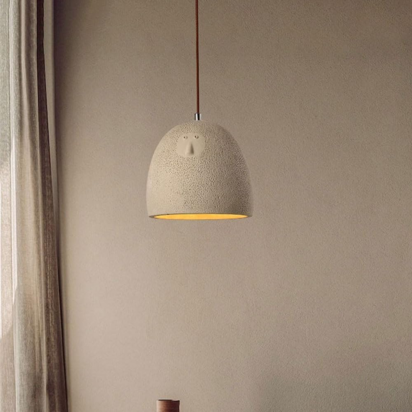 Textured pendant light hanging against a beige wall