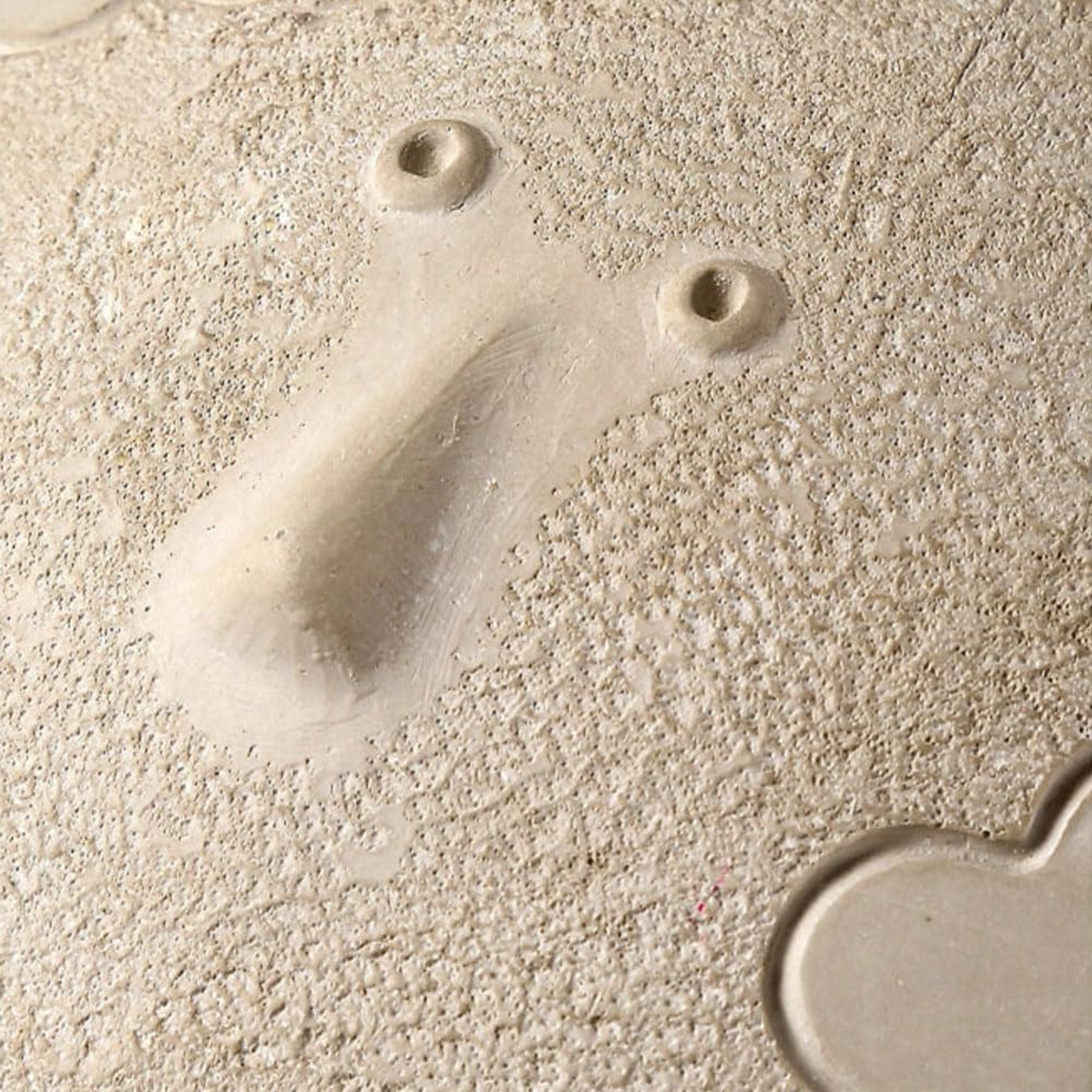 Close-up of a textured beige surface with two small holes and a shadow.