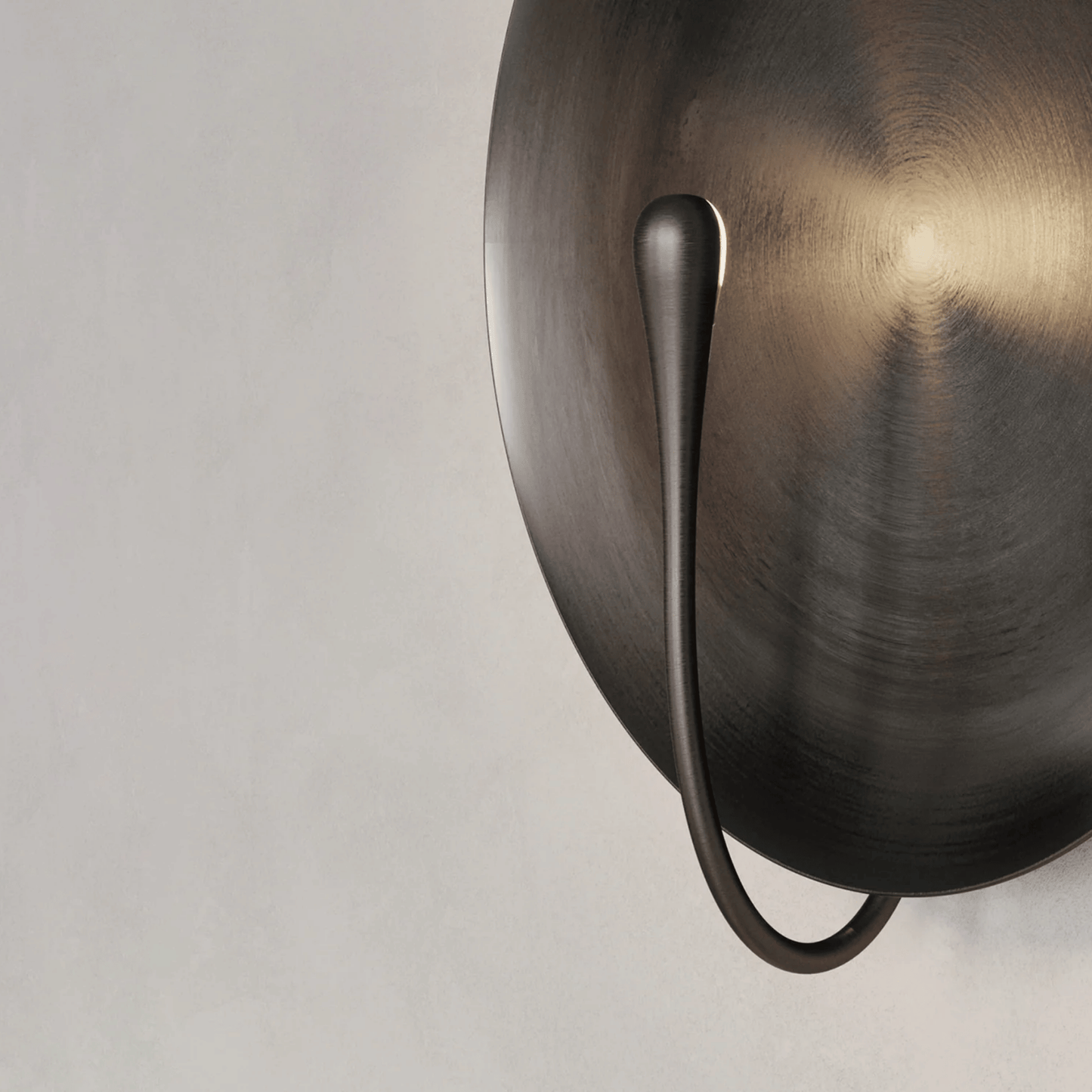 Bronze wall sconce with a single light on a neutral background
