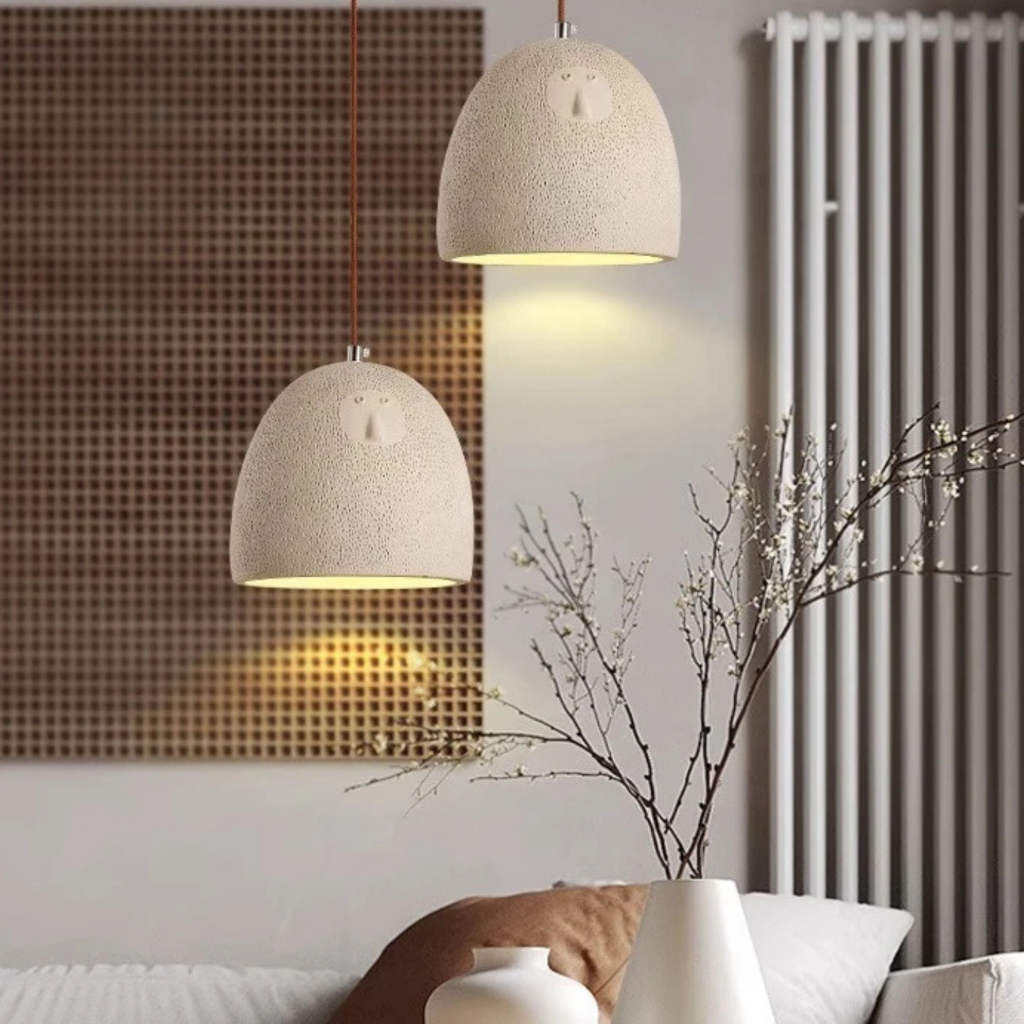 Two beige pendant lights hanging above a sofa with decorative elements.