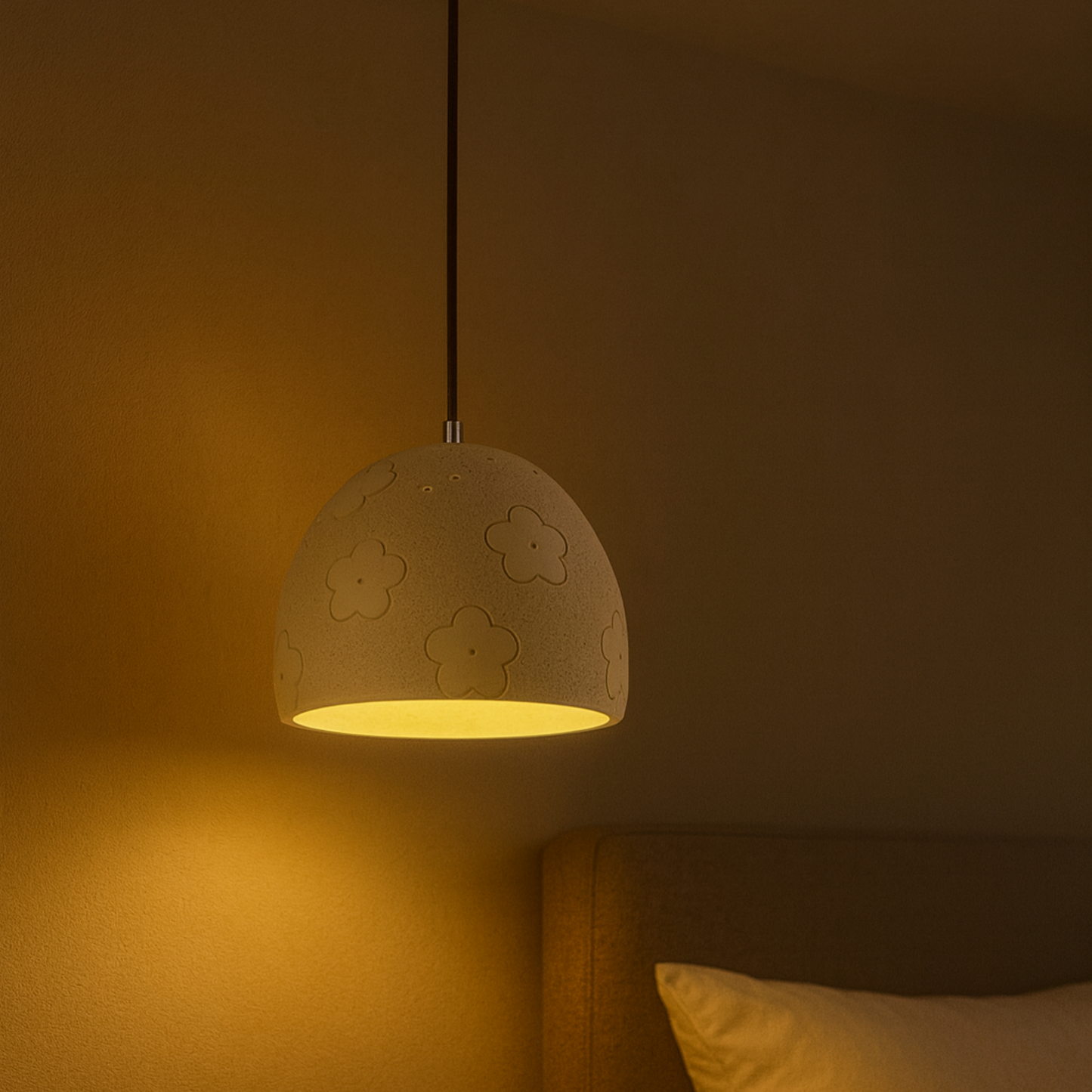 Cement pendant light with floral patterns on a warm-toned wall.