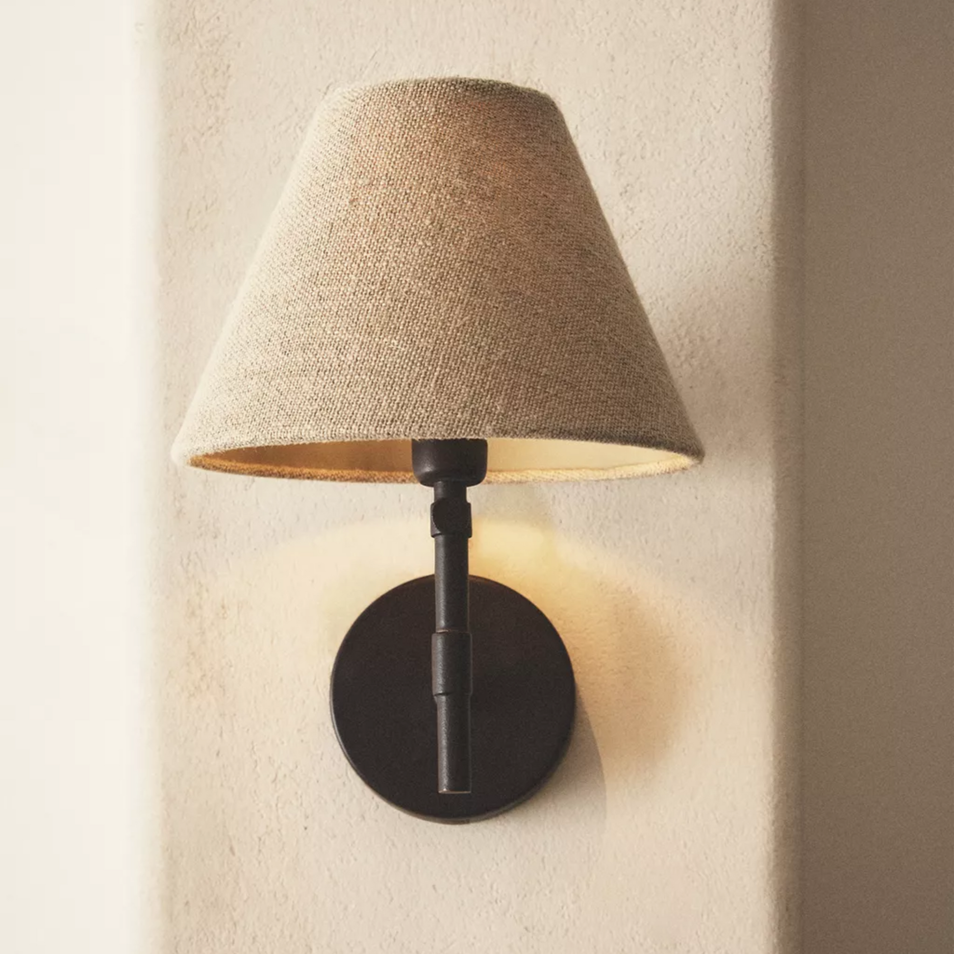 Wall-mounted lamp with a textured brown shade on a neutral wall.
