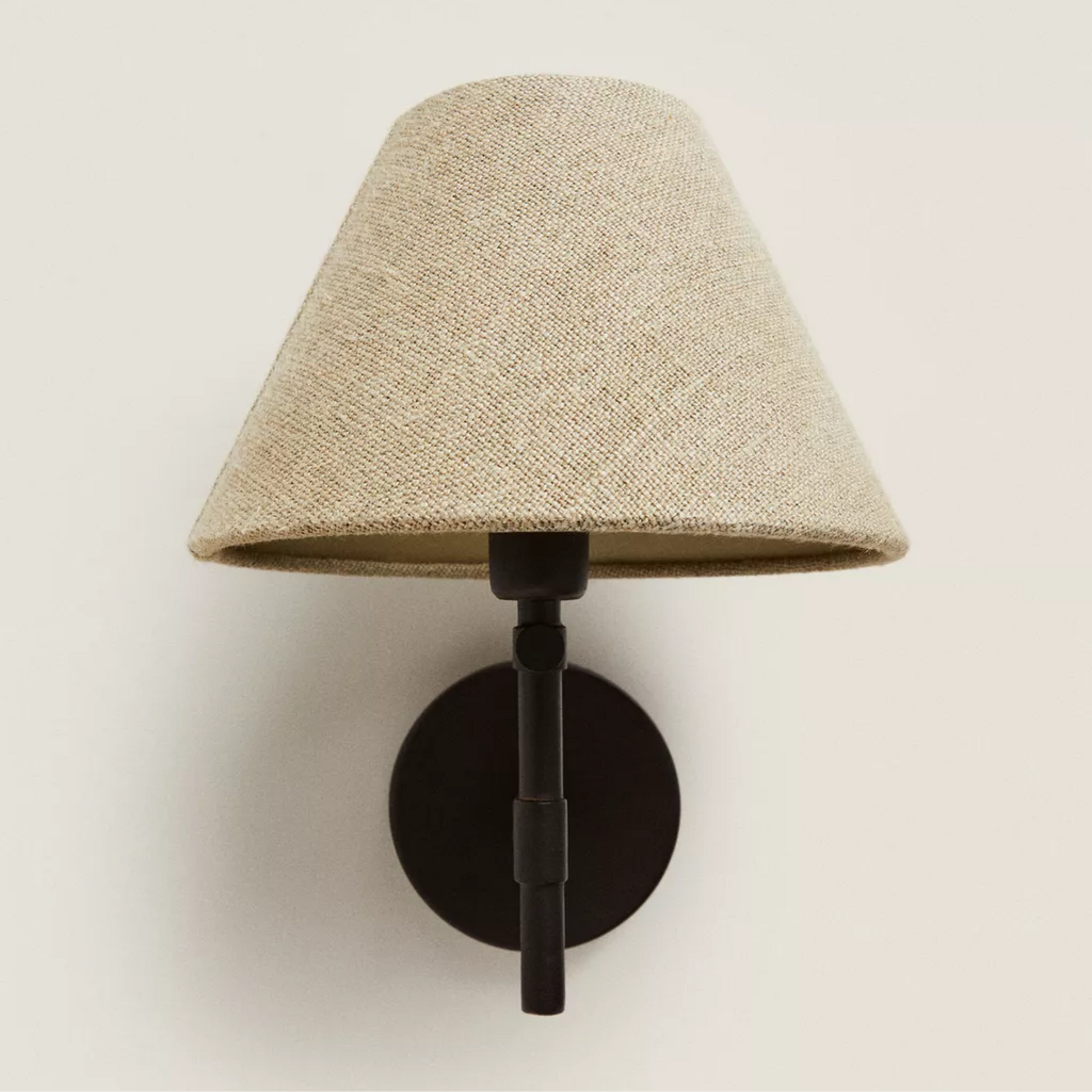 Wall-mounted lamp with a beige shade and black base on a light beige background