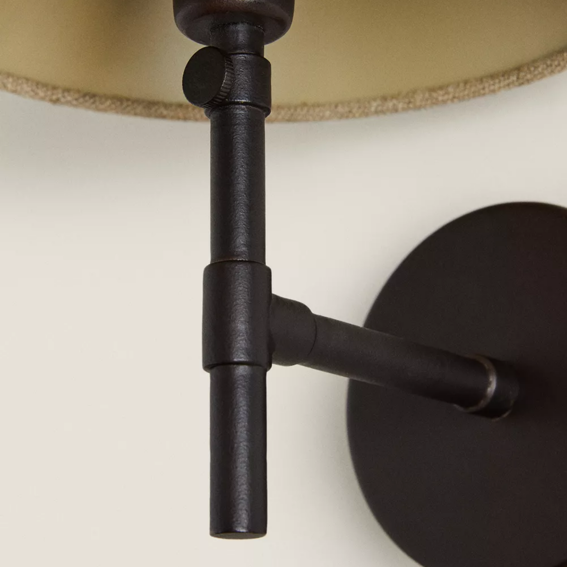 Close-up of a black wall-mounted lamp fixture with a beige lampshade.
