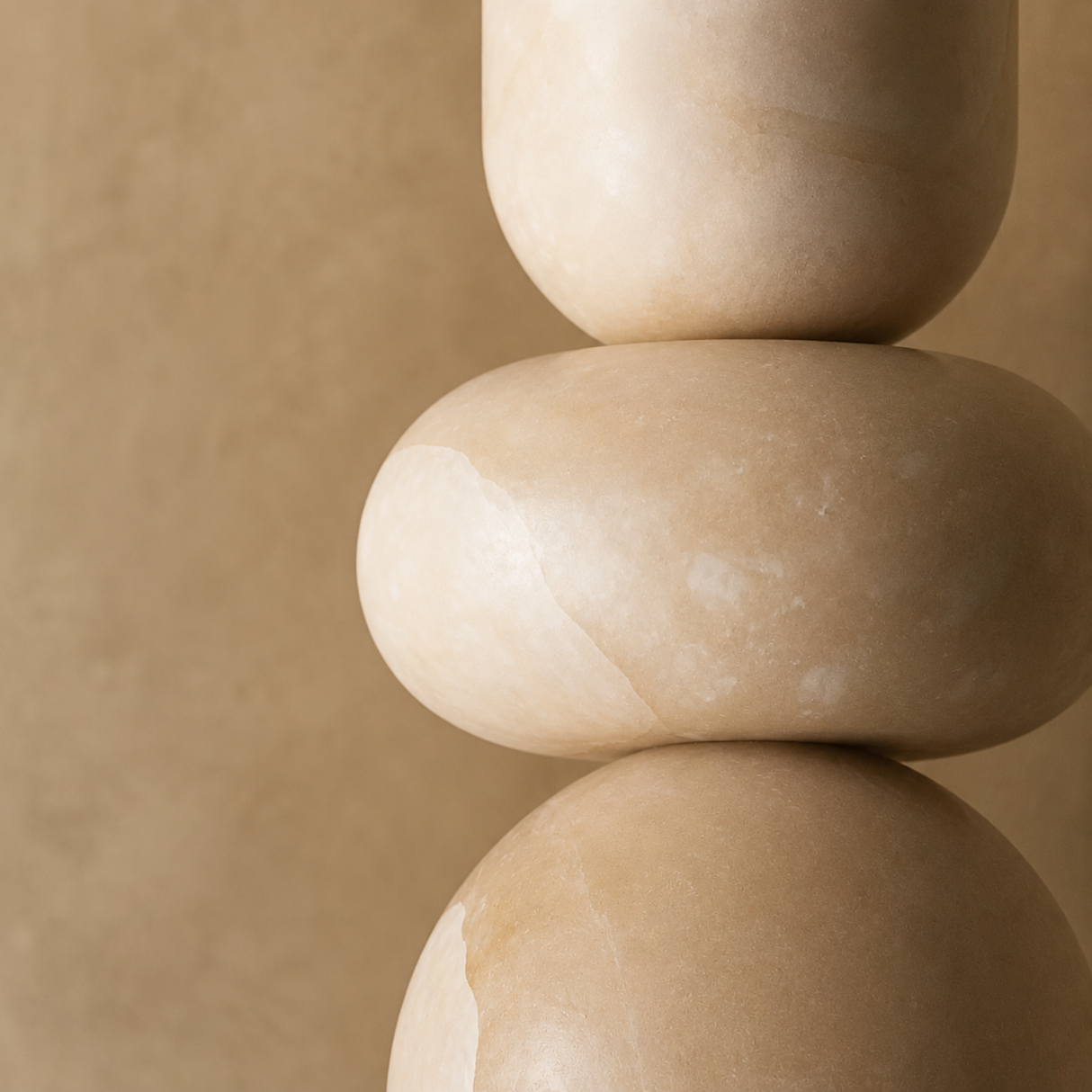 Stack of three beige stones on a matching beige background
