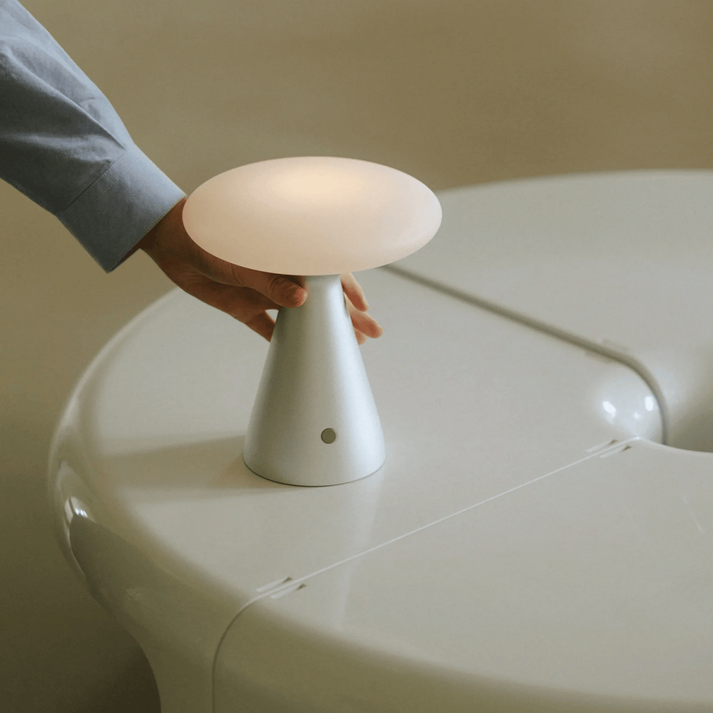 White lamp being held by a hand on a white surface