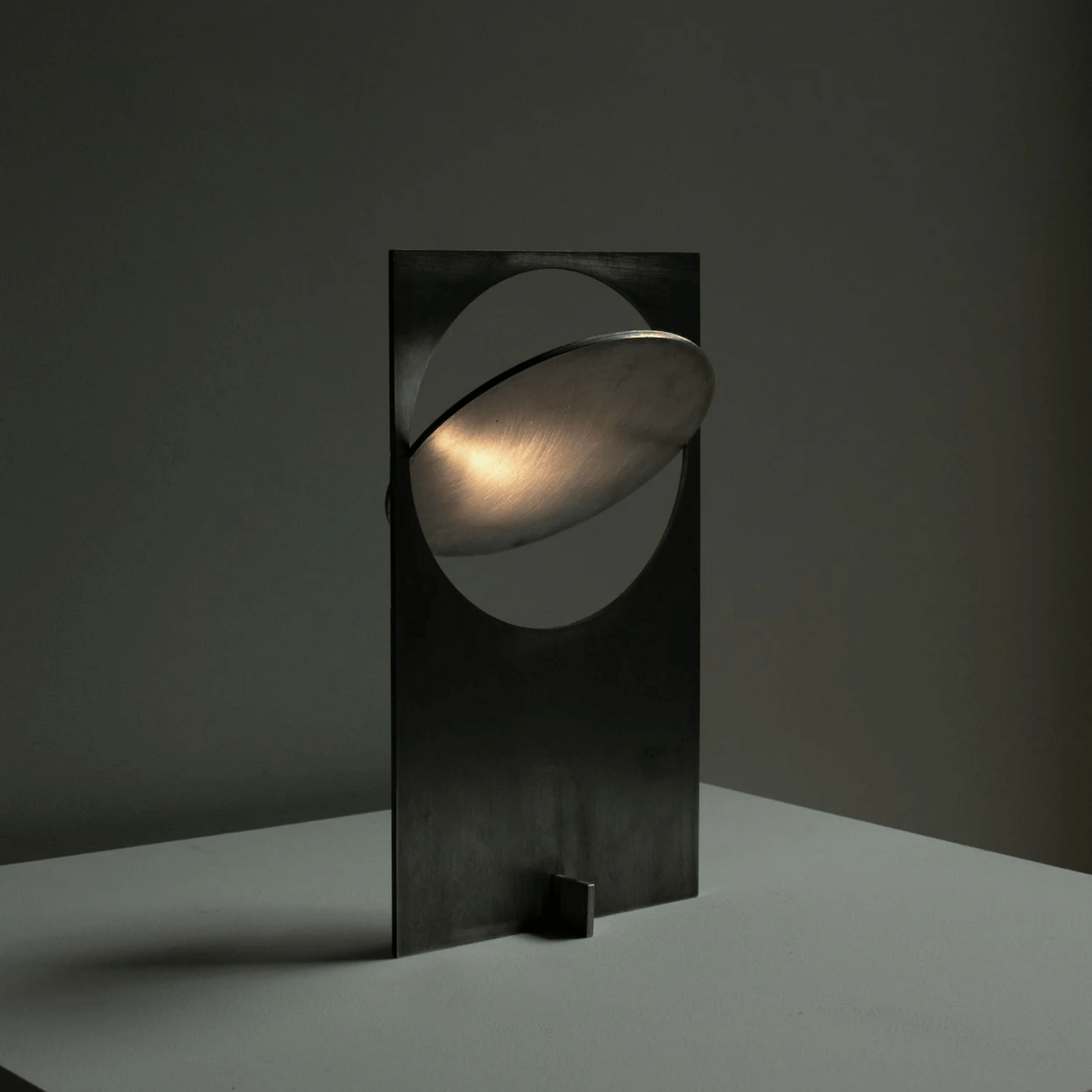 Modern black table lamp with a circular design on a dark background