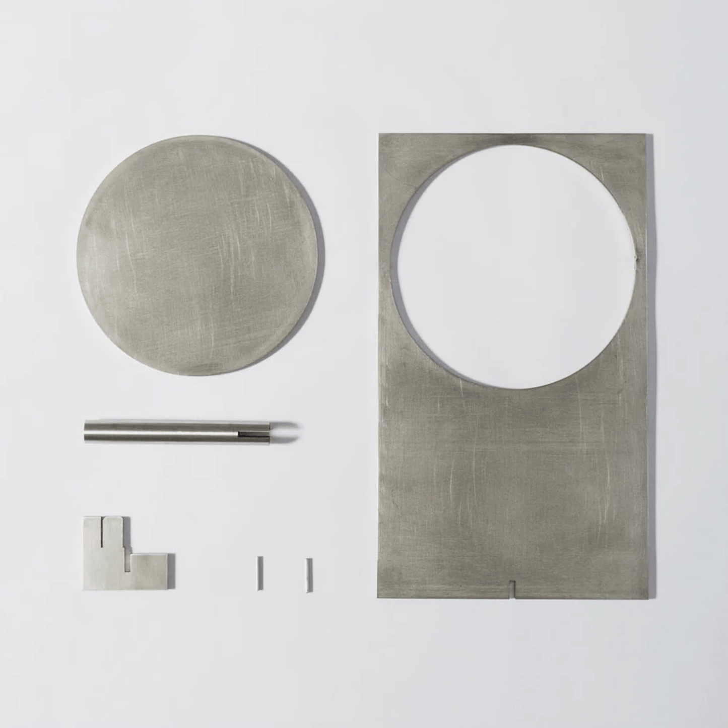 Set of metallic bathroom fixtures including a round mirror, rectangular mirror, towel bar, and hooks on a white background.